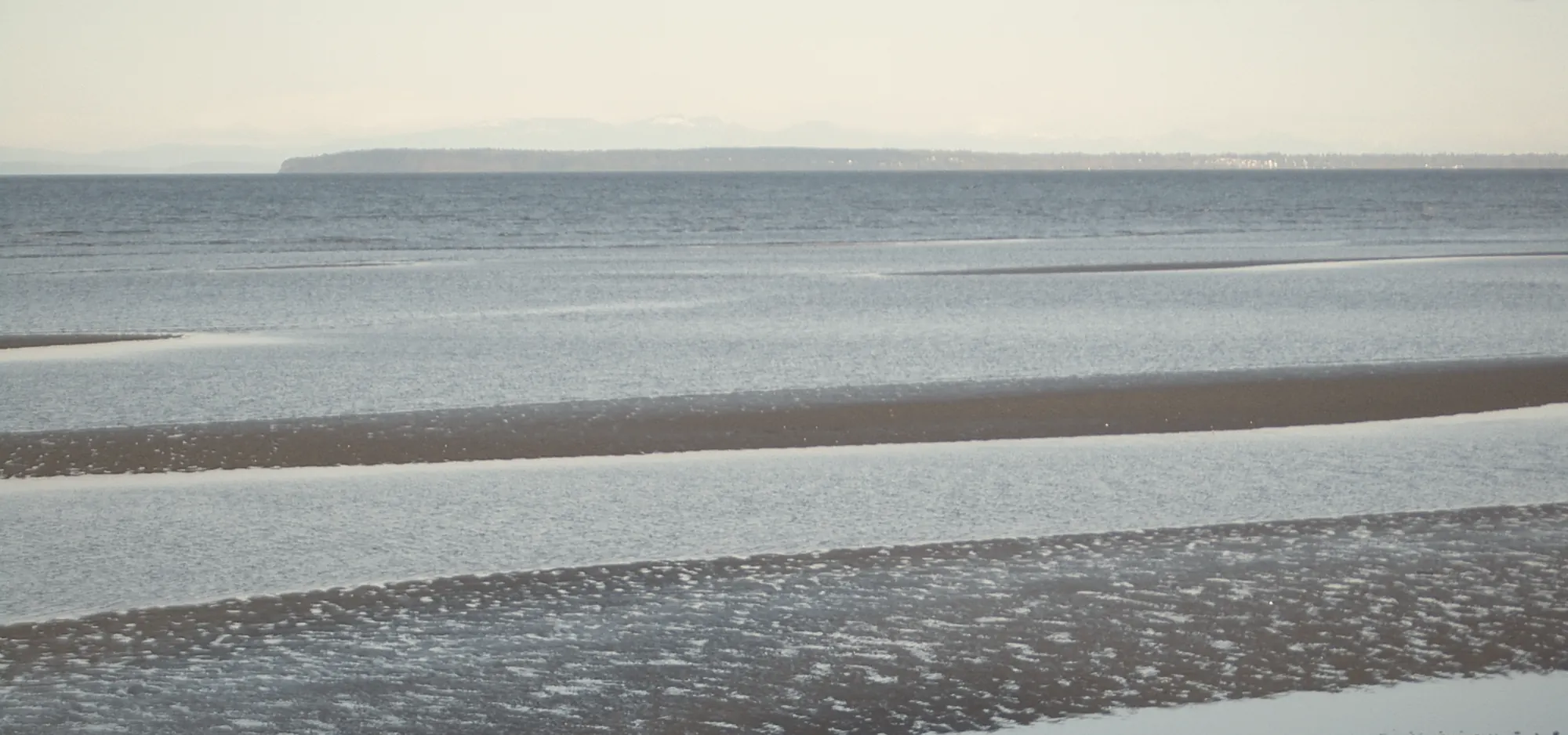 Low tide on Semiahmoo Bay at White Rock, with bands of sand and still water reaching toward the horizon